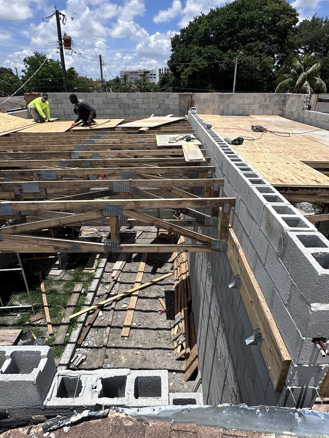 Workers installing plywood over roof trusses
